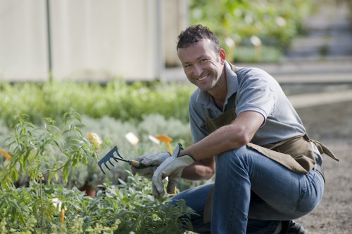 Team member wearing protective gear while pruning a hedge in a public park